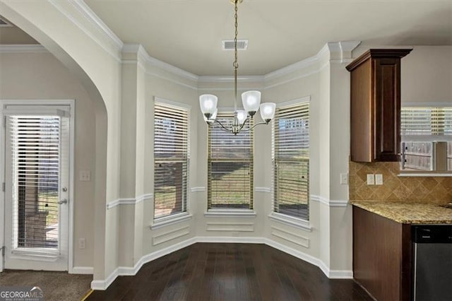 unfurnished dining area with arched walkways, ornamental molding, dark wood finished floors, and visible vents