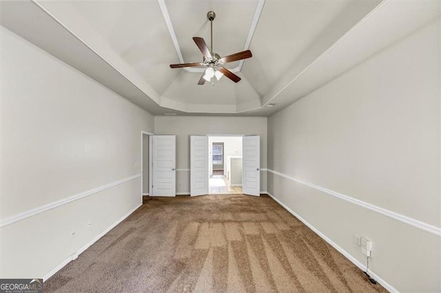 unfurnished bedroom with carpet, baseboards, vaulted ceiling, and a tray ceiling