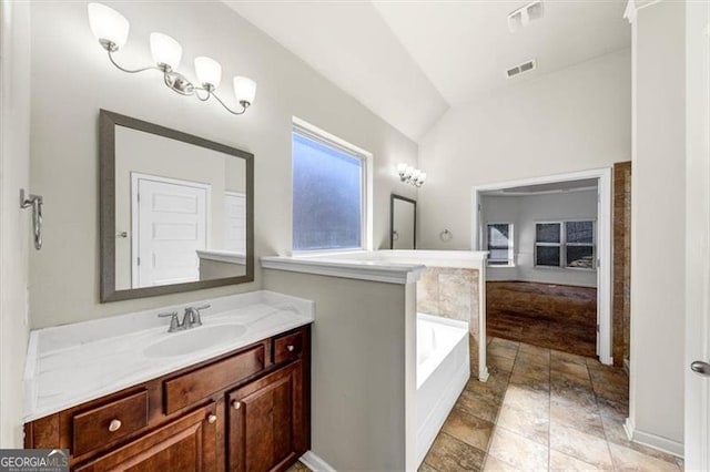 bathroom with visible vents, vaulted ceiling, a bath, and vanity