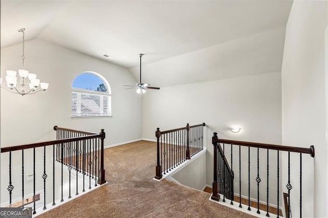 hall featuring lofted ceiling, carpet flooring, an upstairs landing, baseboards, and an inviting chandelier