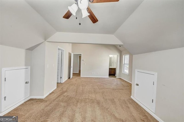 additional living space with lofted ceiling, light carpet, baseboards, and a ceiling fan