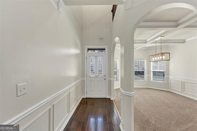 entrance foyer featuring arched walkways, beam ceiling, a wainscoted wall, a decorative wall, and coffered ceiling