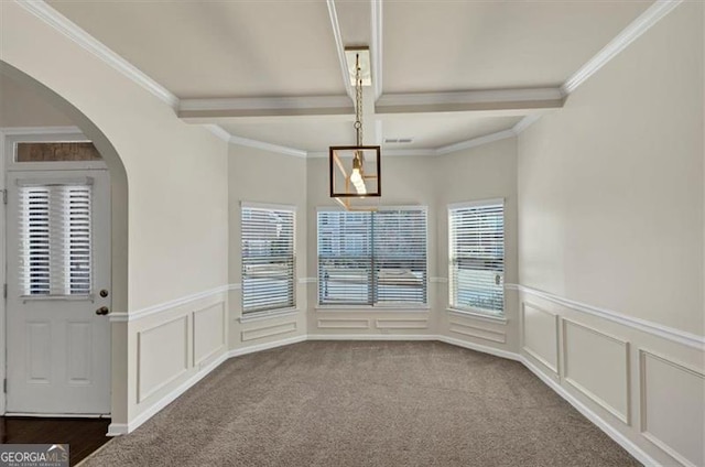 unfurnished dining area with a decorative wall, dark carpet, beam ceiling, and a healthy amount of sunlight