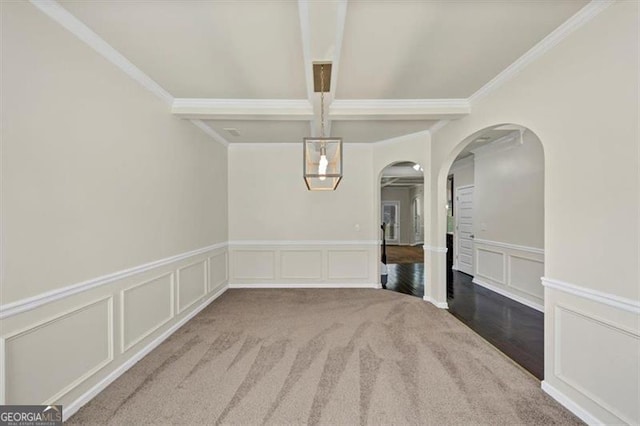 unfurnished dining area with arched walkways, a wainscoted wall, a decorative wall, ornamental molding, and beamed ceiling