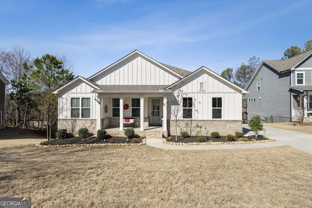 modern farmhouse style home featuring a front lawn, a porch, board and batten siding, and brick siding