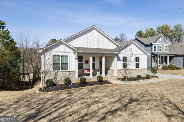 modern farmhouse style home featuring covered porch, roof with shingles, brick siding, and board and batten siding