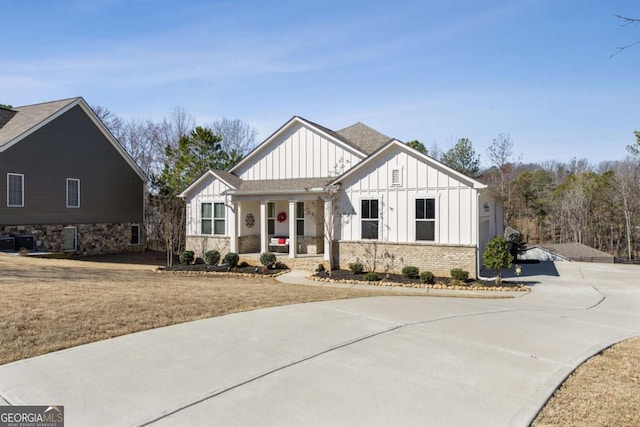 modern farmhouse style home featuring brick siding, a porch, concrete driveway, board and batten siding, and a front yard