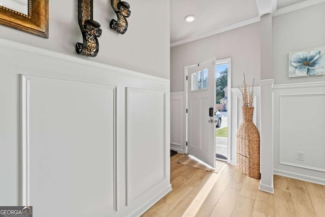 entrance foyer with recessed lighting, a decorative wall, light wood-style flooring, ornamental molding, and wainscoting