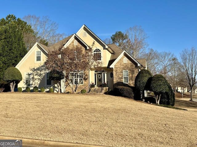 view of front of house featuring stone siding, a front yard, and stucco siding