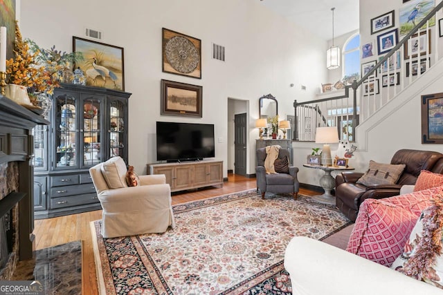 living room with a high ceiling, stairway, wood finished floors, and visible vents