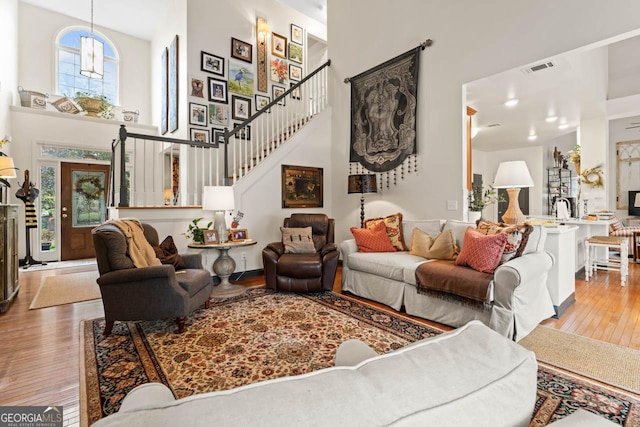 living area featuring wood-type flooring, a towering ceiling, and stairs