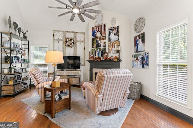 living area featuring lofted ceiling, wood-type flooring, baseboards, and ceiling fan