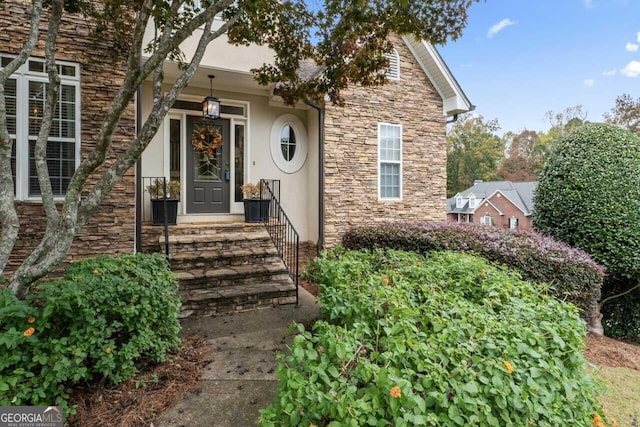 doorway to property featuring stone siding and stucco siding