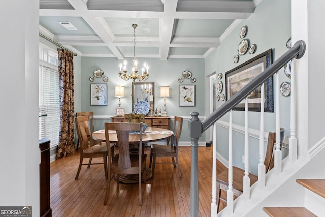 dining space featuring an inviting chandelier, wood-type flooring, stairs, and beamed ceiling