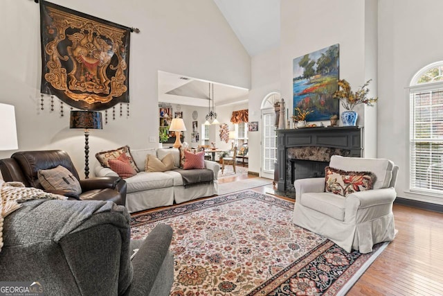 living room featuring high vaulted ceiling, hardwood / wood-style floors, and a premium fireplace