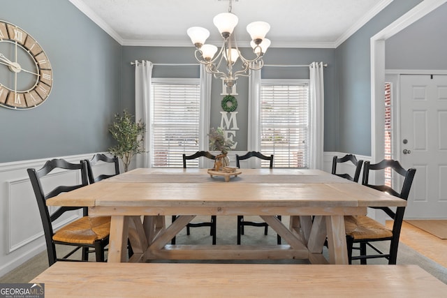 dining room with ornamental molding, a wainscoted wall, and a notable chandelier