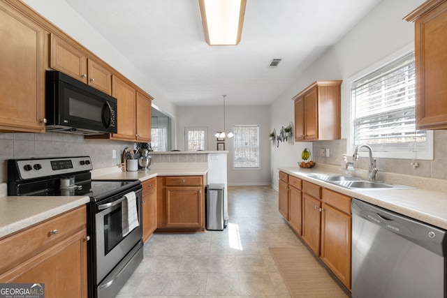 kitchen with stainless steel appliances, a sink, a peninsula, and tasteful backsplash