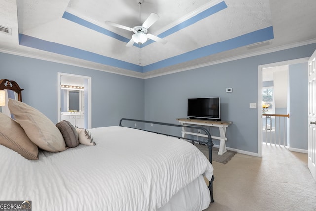 carpeted bedroom featuring ensuite bathroom, ornamental molding, a raised ceiling, and baseboards