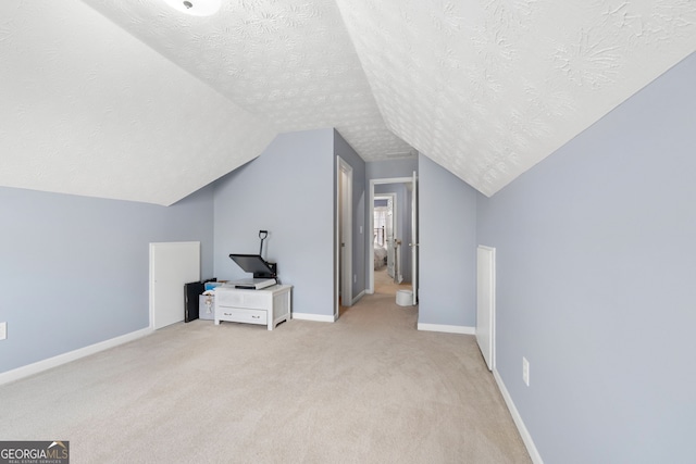 additional living space featuring light carpet, baseboards, vaulted ceiling, and a textured ceiling