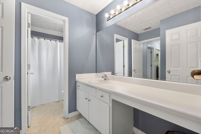 bathroom featuring visible vents, toilet, a textured ceiling, vanity, and baseboards