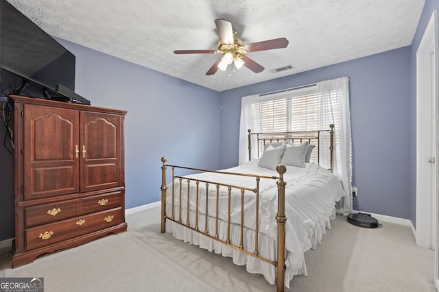 bedroom featuring baseboards, visible vents, light colored carpet, ceiling fan, and a textured ceiling