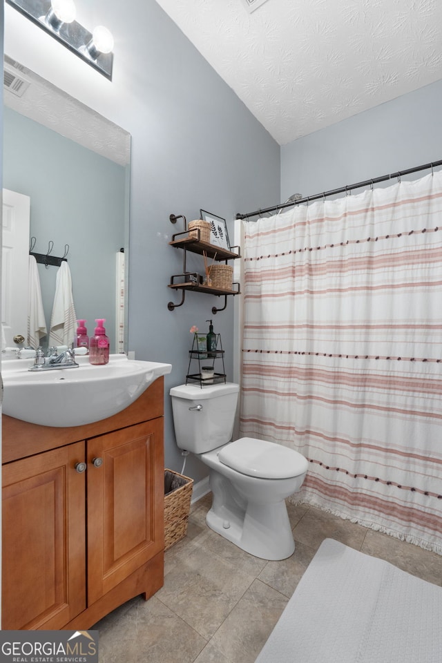 bathroom featuring a textured ceiling, tile patterned flooring, toilet, vanity, and visible vents