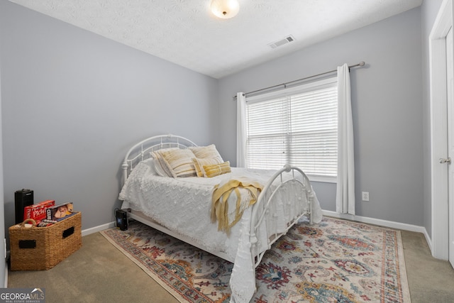 bedroom with carpet, visible vents, a textured ceiling, and baseboards