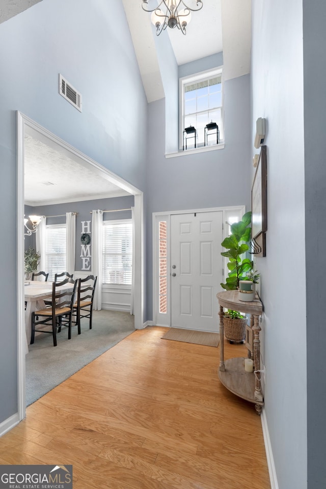 entrance foyer with plenty of natural light, visible vents, a notable chandelier, and wood finished floors