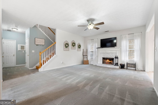 unfurnished living room featuring stairway, a brick fireplace, carpet flooring, and a wealth of natural light