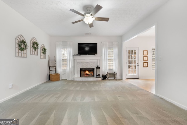 unfurnished living room with a brick fireplace, carpet flooring, and a wealth of natural light