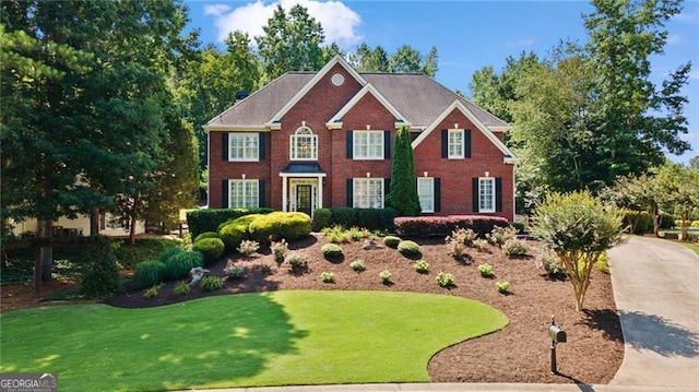 colonial inspired home featuring a front lawn and brick siding