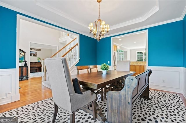 dining room featuring a raised ceiling, wainscoting, and an inviting chandelier