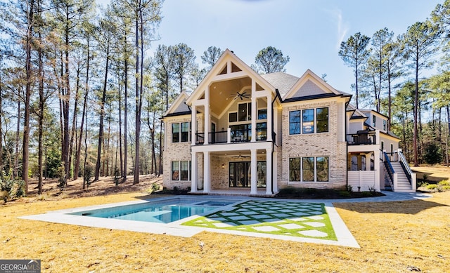 rear view of house with ceiling fan, stairs, a lawn, a balcony, and a patio