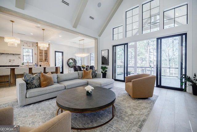 living room featuring visible vents, high vaulted ceiling, an inviting chandelier, beamed ceiling, and light wood-type flooring