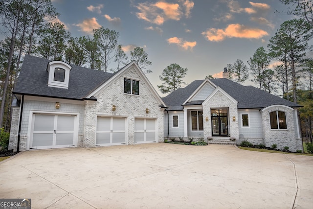 view of front of house with brick siding, concrete driveway, a chimney, and a shingled roof