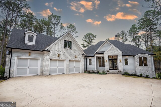 view of front of home with brick siding, roof with shingles, concrete driveway, and a chimney