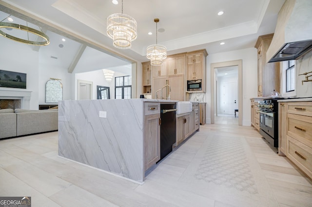 kitchen with light brown cabinetry, custom range hood, a tray ceiling, black appliances, and a kitchen island with sink