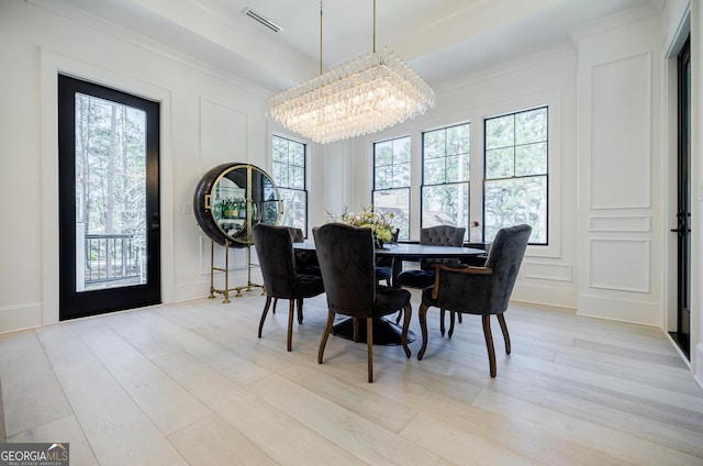 dining space featuring visible vents, a notable chandelier, ornamental molding, a decorative wall, and light wood finished floors