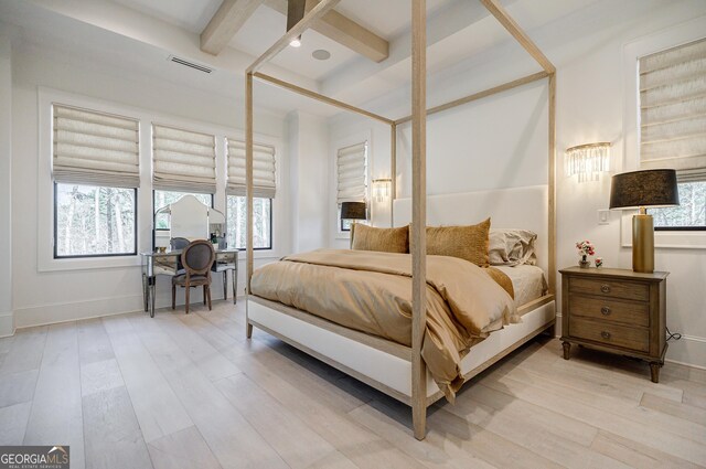 bedroom featuring visible vents, beam ceiling, multiple windows, and light wood finished floors