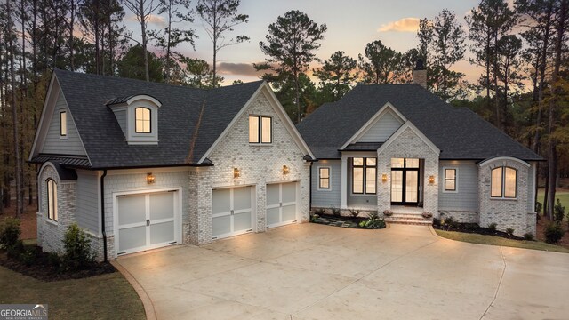 french country style house featuring a garage, brick siding, and driveway