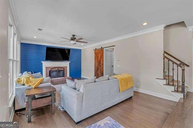 living area with wood finished floors, stairway, baseboards, and a barn door