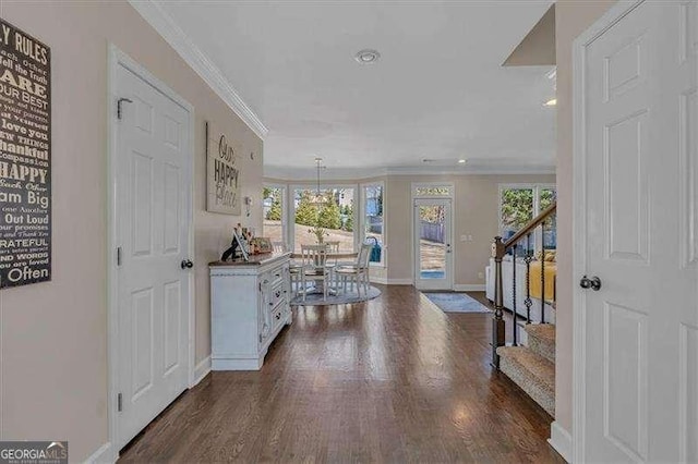 entrance foyer with plenty of natural light, stairs, ornamental molding, and dark wood-type flooring