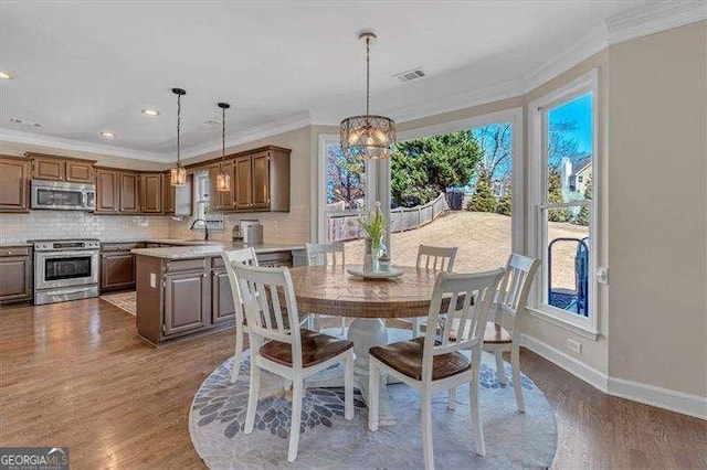 dining area featuring crown molding, dark wood-style flooring, and plenty of natural light