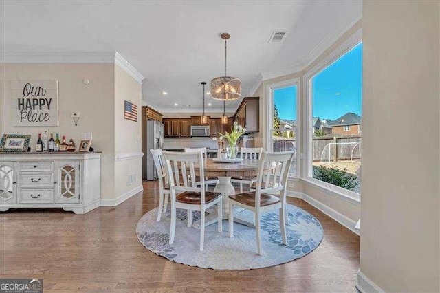 dining space featuring dark wood-type flooring, crown molding, baseboards, and an inviting chandelier