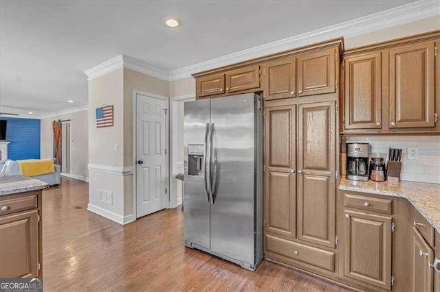 kitchen with light wood-style floors, stainless steel fridge, ornamental molding, and tasteful backsplash