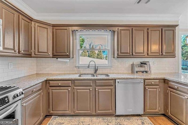 kitchen with crown molding, tasteful backsplash, light wood-style flooring, appliances with stainless steel finishes, and a sink