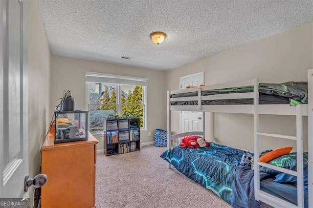 bedroom featuring carpet floors, visible vents, and a textured ceiling