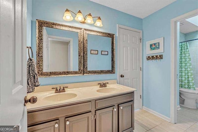 full bathroom featuring toilet, double vanity, baseboards, and a sink