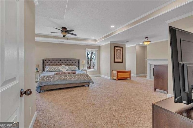 bedroom featuring ornamental molding, a tray ceiling, a textured ceiling, carpet floors, and a fireplace