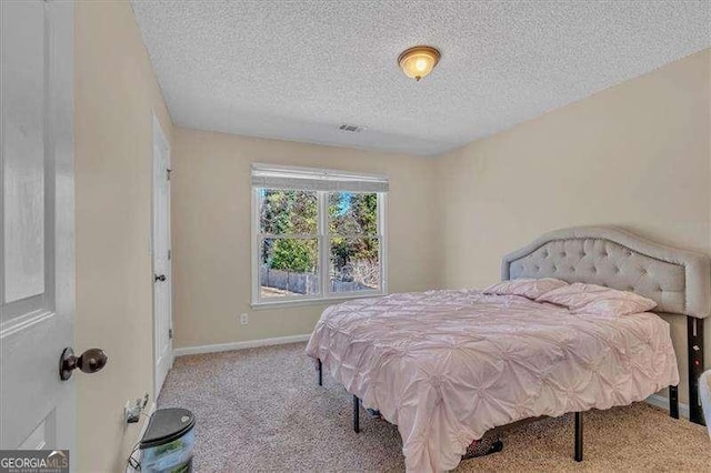 bedroom with a textured ceiling, carpet, visible vents, and baseboards